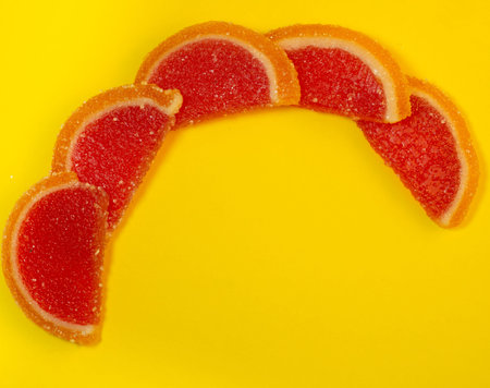 Fruit jelly in the form of grapefruit slices on a yellow background. Sweets on the table. Background...