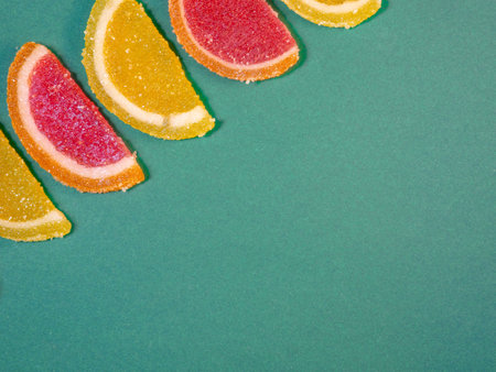 Fruit jelly in the form of orange slices on a green surface. Background from sweets. Background from marmaladeの写真素材