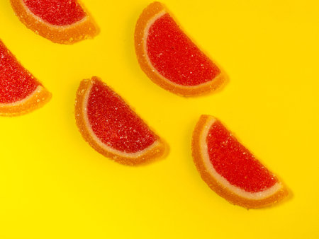Fruit jelly in the form of grapefruit slices on a yellow background. Sweets on the table. Background from marmalade. Fruit - sweetsの写真素材