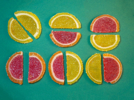 Fruit jelly in the form of orange slices on a green surface. Background from sweets. Background from marmaladeの写真素材