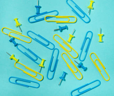 Colored paper clips on paper. Office supplies. Business goods. Colorful office supplies.の写真素材