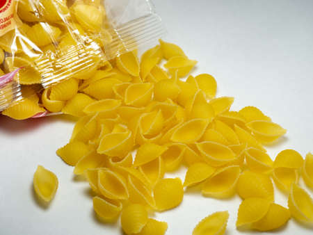 Shell-shaped pasta spills out of the package. Italian food. Cooking food. durum wheatの写真素材