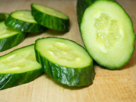 A smooth, medium-sized cucumber cut into slices. Cucumber on a cutting board. Vegetable isolate. Fresh ripe vegetable before cooking dinner.の写真素材