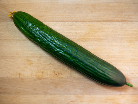 Smooth medium cucumber. Cucumber on a cutting board. Cucumber flower. Fresh ripe vegetable before cooking dinnerの写真素材