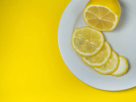 Sliced ââlemon on a plate on a yellow background. Citrus slices on the table. Bright background. Healthy fortified diet food. sour product.の写真素材