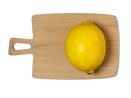A whole lemon on a small cutting board on a white background. Citrus on the table. bright background. Healthy fortified food for a vegetarian lemon isolateの写真素材