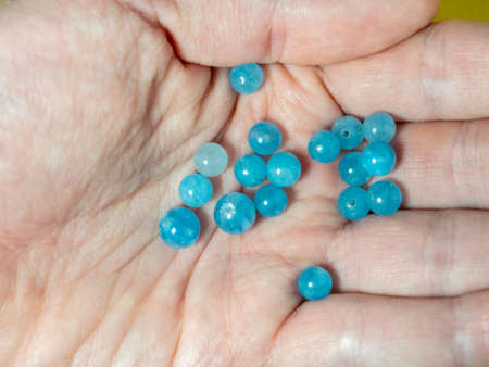 Blue beads on the palm. Chalcedony. Bijouterie. Items for needlework. Stones in the workshopの写真素材