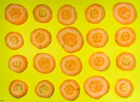 cut carrot on a yellow background. background of carrot slices. Vegetarian food. vitamins. Fresh vegetables on the table. cooking dinnerの写真素材