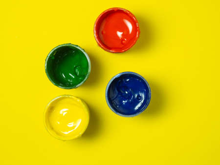 Jars of paint on a yellow background. Banks of gouache. Bright. creative background. artist's workshop.の写真素材