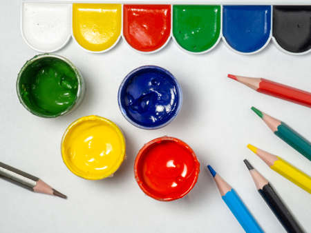 Jars with yellow, green, red paint and pencils on a white background. Banks of gouache. Bright. creative background. artist's workshop.の写真素材