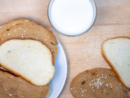 Pieces of rye bread with a glass of milk on a plate. Healthy breakfast. Bakery products with sesame seeds.の写真素材