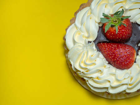 Cake with butter cream and strawberries. Cake on a yellow background. treat for tea. Sweetsの写真素材
