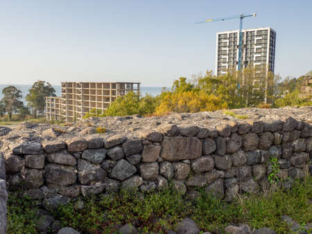 Construction of a modern house next to the ancient masonry. old and new. Ancient parts of the temple. Part of an ancient masonry. Remains of history.の写真素材