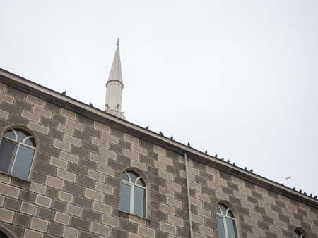 Mosque wall with doves. The birds are sitting on the wall. Minaret of the mosqueの写真素材