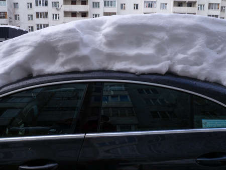 street photo. Big snowdrifts in the city. Thick layer of snow on the car. after bad weatherの写真素材