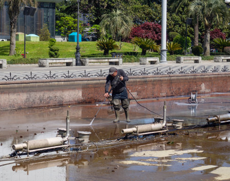 Batumi, Georgia. 23/05/2022 worker cleans the mechanism of the fountain. drained. cleaning work. Dirty bottom of the city fountainのeditorial素材