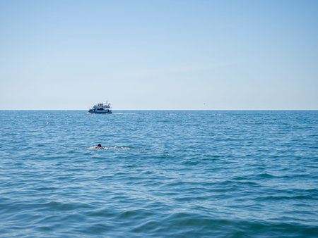 The man swims towards the boat. Seascape. resort place. Place for rest. Boat on the water
