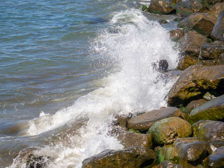 Waves with splashes fall on large stones. Shore view. Beautiful stones that strengthen the shore from the surf. Powerful coastline. sea foam. The excitement of the sea. Turkishの写真素材