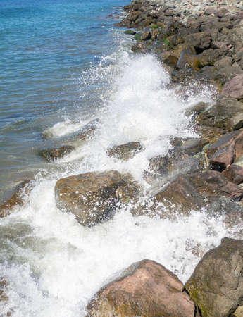 Waves with splashes fall on large stones. Shore view. Beautiful stones that strengthen the shore from the surf. Powerful coastline. sea foam. The excitement of the sea. Turkishの写真素材