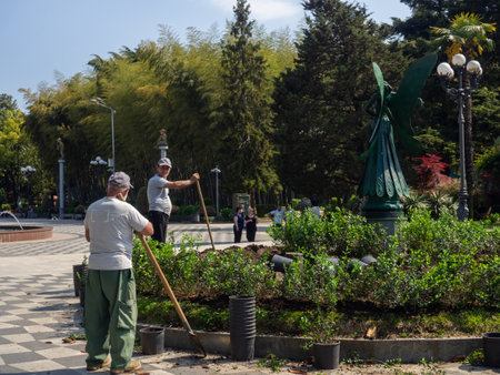 Batumi, Georgia. 05.30.2022 Landscaping of the park. Work in the garden. city gardener. Man at work. Planting plants in a beautiful park. Shovelのeditorial素材