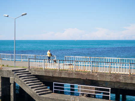 Lonely man on the pier. Rest on the seashore. Escape from everyday life. Lonelinessの写真素材