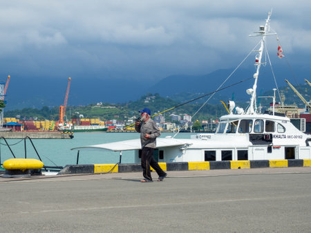 Batumi, Georgia. 06.21.2022 Fishermen in the port with fishing rods. Men on vacation. hobby. weekend pass time. Man goes fishingのeditorial素材