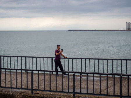 Hope, Turkey. 22/07/2022 A man takes a selfie on the Black Sea pier. landscape. Man on the background of the sea. Rest on the water. Photographing on the phoneのeditorial素材