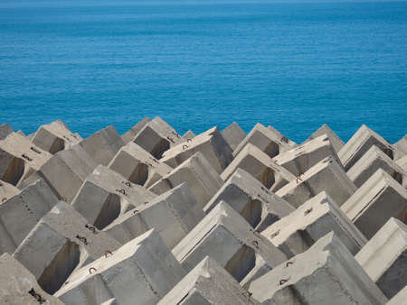 Concrete breakwaters and heaps of stones on the shore. Stone against the waves. Shore protection. concrete structuresの写真素材