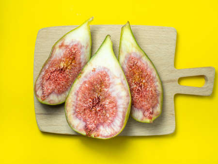 sliced figs on a cutting board. Juicy ripe fruit on a yellow background. Diet food. Figure isolate. Seeds inside. Bright picture. fruit conceptの写真素材