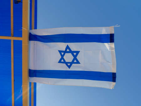 The flag of Israel flutters on a beam under the roof. Flag under the trend of the restaurant on the seashore. Decoration for a bar. flag against the skyの写真素材