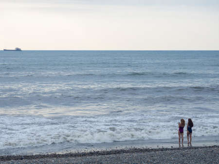 man and element. Girls on the beach in bad weather. Bathing is prohibited. high waves. Beautiful landscape in cloudy weather. rest places. Resort on the sea. Photographed on the beach on the phone.の写真素材