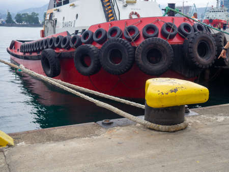 Protection of the sides of the ship in the form of old tires. Scale for submerging a ship in water. Tugboat in the port. The ship is parked. Tires from a car. Wheel reuse.の写真素材