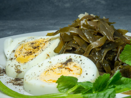 Seaweed salad and cut boiled egg. Dish on the table in a plate. Pepper half of an egg. Parsley greens as decoration. Healthy snack foodsの写真素材