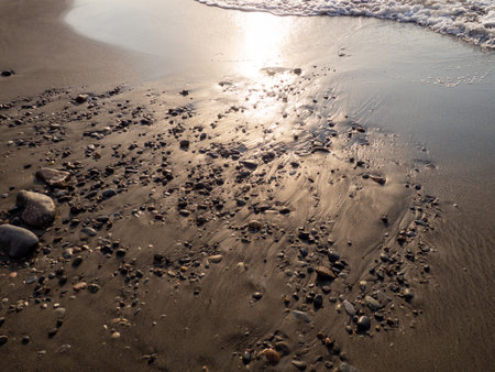 Stones on the sandy beach. Quiet place. The silence of the waves Edge of the coast. Background of sand and stone. Black sand on the beach. bathing place.の写真素材