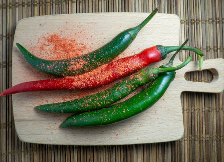 Green chili and ground red pepper on a cutting board. Green spicy chili pepper on the table. Cooking spicy dishes. hot peppers. Acute ingredient for lunch. green vegetable. ground paprikaの写真素材