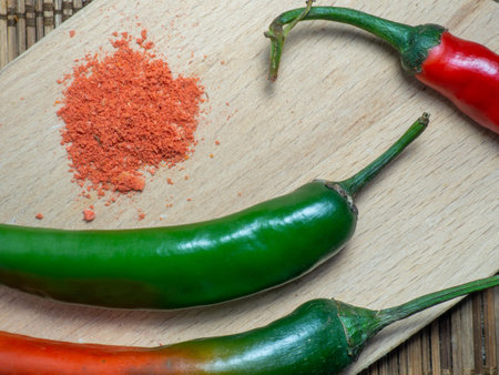 Green chili  and ground red pepper on a cutting board. Green spicy chili pepper on the table. Cooking spicy dishes. Hot peppers. Acute ingredient for lunch. Green vegetable. Ground paprikaの写真素材