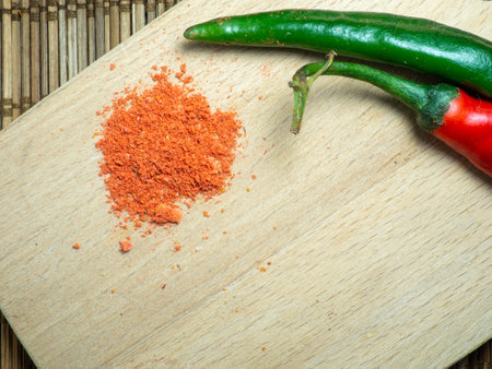 Green chili and ground red pepper on a cutting board. Green spicy chili pepper on the table. Cooking spicy dishes. hot peppers. Acute ingredient for lunch. green vegetable. ground paprikaの写真素材