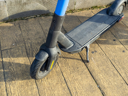 A used scooter is parked on the sidewalk. Part of a scooter close-up. Leisure. Movement on two-wheeled transport. Electric scooter in idle positionの写真素材
