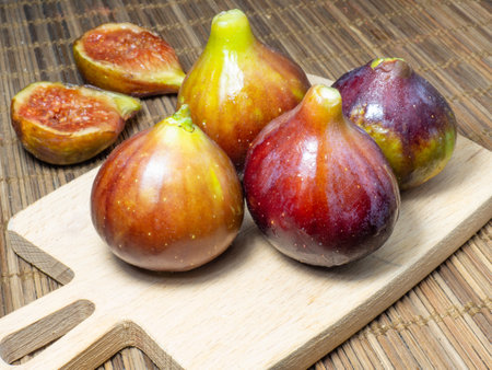 Juicy ripe figs on a cutting board. Halves of figs. Southern fruits on the table. Sliced purple fruits.Pulp of figs on the board in the kitchen.の写真素材