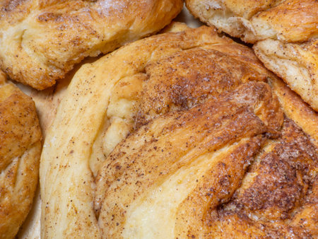 Wicker bun with cinnamon and sugar. Bread product of an unusual shape. homemade baking. Buns with a ruddy crust. Closeup of foodの写真素材