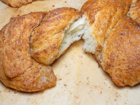 Wicker bun with cinnamon and sugar. Broken wicker bun. Bread product of an unusual shape. homemade baking. Buns with a ruddy crust. Close-up food. Pulp baking.の写真素材