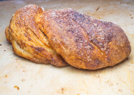 Wicker bun with cinnamon and sugar. Bread product of an unusual shape. Homemade baking. Buns with a ruddy crust. Closeup of foodの写真素材