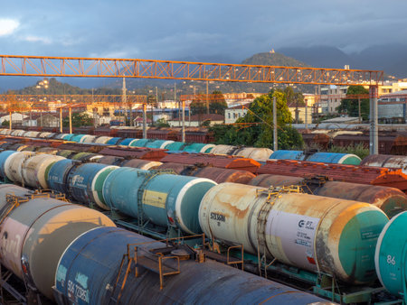 Batumi, Georgia. 10.18.2022  Tanks with fuel on the railway tracks at sunset. Sunset at the train station. The cargo part of the station is an industrial zone against the backdrop of mountains. Fuel wagons. Cargo transportationのeditorial素材