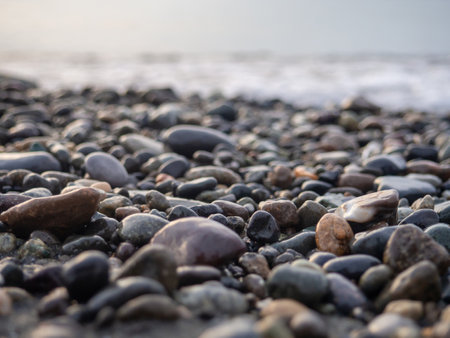 Pebbles on the seashore close-up. rocky beach. Stones close-up with bokeh. gray natural background. Autumn on the coast. Waves and wet pebblesの写真素材
