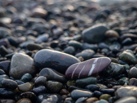 Pebbles on the seashore close-up. Rocky beach. Stones close-up with bokeh. Gray natural background. The concept of rest on the seashore. The Velvet season. Autumn on the seashore. Waves and wet pebblesの写真素材