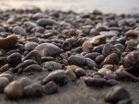 Pebbles on the seashore close-up. rocky beach. Stones close-up with bokeh. gray natural background. Autumn on the coast. Waves and wet pebblesの写真素材