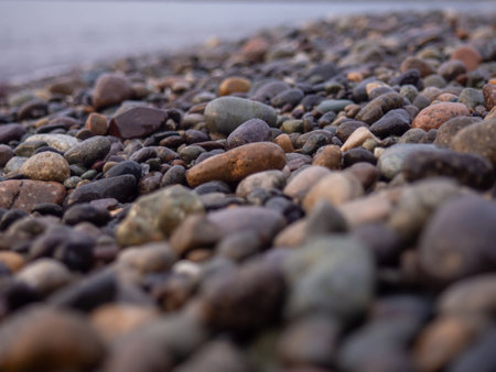 Pebbles on the seashore close-up. rocky beach. Stones close-up with bokeh. gray natural background. The concept of rest on the seashore. The Velvet season. Autumn on the coast. Waves and wet pebblesの写真素材
