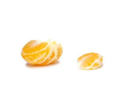 Unripe tangerine. Peeling a tangerine. Green fruit on a white background. Sour ingredient. Citrus isolate. Sliced green mandarin. Useful fruit.の写真素材