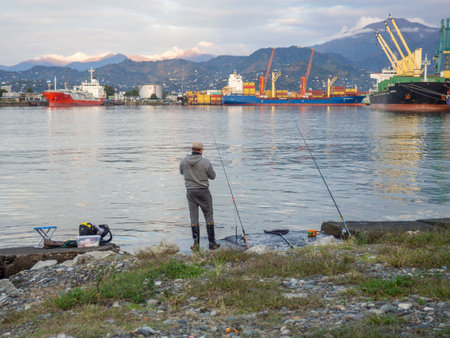 Fisherman on a concrete pier. A fisherman in the port catches fish. city fishing. hobby men. Atmosphere of an Asian port.の写真素材