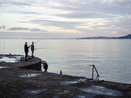 Batumi, Georgia. 28/10/2022 Fisherman on a concrete pier. A fisherman in the port catches fish. city fishing. hobby men. Atmosphere of an Asian port.のeditorial素材